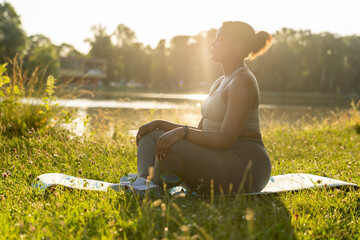African American woman practicing meditating at the park - obrazy, fototapety, plakaty