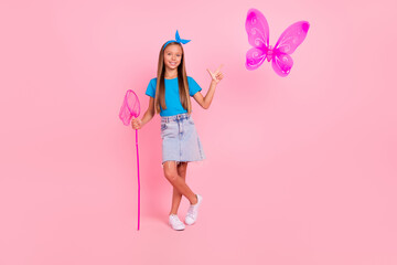 Full length photo of cheerful charming person hand hold net direct finger butterfly isolated on pink color background