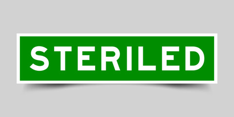 Green color square shape sticker label with word steriled on gray background