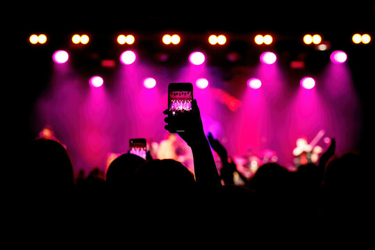 Taking photos of the concert stage, live concert, and music festival due to mobile phone.