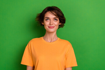 Photo of stunning dreamy young lady wear orange outfit looking up empty space smiling isolated green color background
