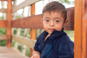 Portrait of a child with Down syndrome looking at the camera with his mouth smeared with candy.