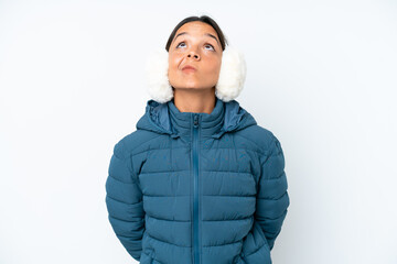Young hispanic woman wearing a winter earmuffs isolated on white background and looking up
