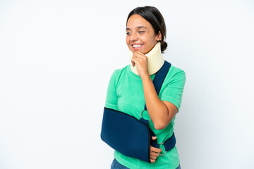 Young hispanic woman wearing a neck brace and sling isolated on white background looking to the...