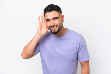 Fototapeta premium Young Arab handsome man isolated on white background listening to something by putting hand on the ear