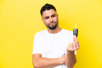 Young Arab man holding car keys isolated on yellow background with sad expression
