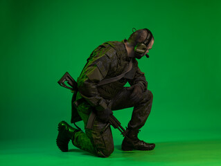 soldier in the studio on a green background with colored light. a man in military uniform with a gun, rifle or machine gun. military. airball player