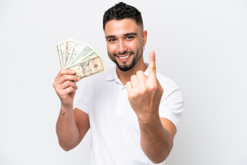 Young Arab man taking a lot of money isolated on white background doing coming gesture