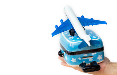 small toy ceramic suitcase in woman hand isolated on light white background.mini santa claus hat on suitcase handle or toy passenger airplane over.travel tourism christmas trip summer sea beach