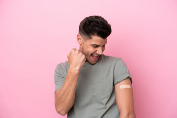 Young caucasian man wearing band-aids isolated on pink background celebrating a victory
