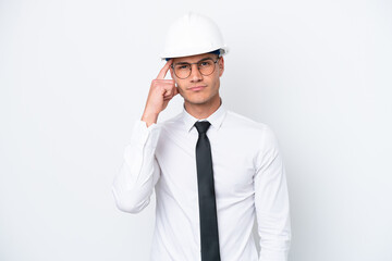 Young architect caucasian man with helmet and holding blueprints isolated on white background thinking an idea