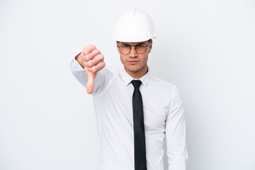 Young architect caucasian man with helmet and holding blueprints isolated on white background showing thumb down with negative expression