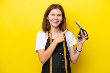 Young seamstress English woman isolated on yellow background pointing to the side to present a product