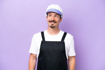 Fishmonger man wearing an apron isolated on purple background thinking an idea while looking up