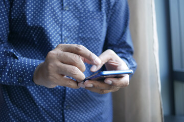 Close up of young man hand using smart phone.