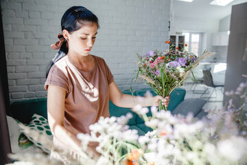 young brunette European female florist makes a bouquet of colorful flowers in her flower studio