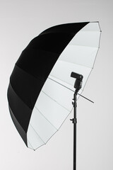 Camera flash head mounted on stand with umbrella light reflector in photography studio