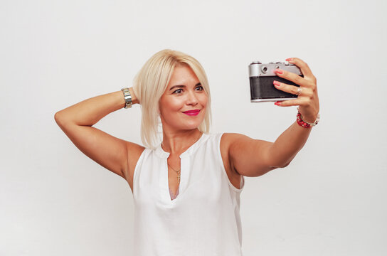 Middle-aged woman with white hair takes a selfie with a camera