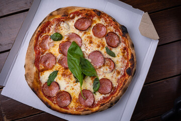 Homemade Pepperoni, Salami Pizza with basil, tomatoes, cheese on wooden table. ready to eat