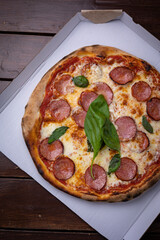 Homemade Pepperoni, Salami Pizza with basil, tomatoes, cheese on wooden table. ready to eat