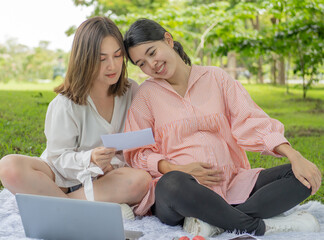 Happy pregnant woman lesbian family relaxing in park. Homosexual people has affectionate...