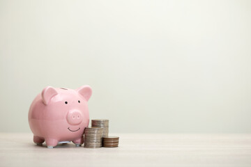 pink piggy bank smiling and coins on the table, for saving money wealth, and financial concepts,...