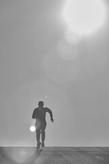 Fototapeta premium man running towards the sun during sunset