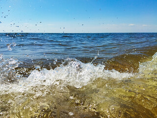 Large splashes from the sea waves against the blue sky. Seascape Light blue sky. Splashes and drops in the foreground