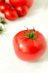 Red ripe tomatoes of different sizes on a white background. Healthy food concept. Vertical orientation. Selective focus.