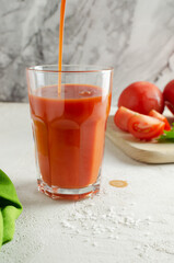 Tomato juice is poured in a transparent glass glass with chopped omelets on a white background. The concept of vegetarian food. Vertical orientation. Selective focus.