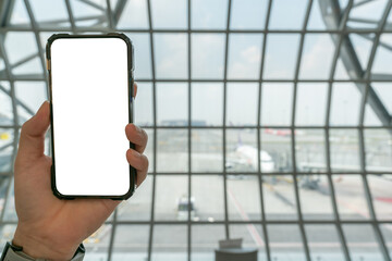 Mobile screen blank on hand at airport check-in counter background.