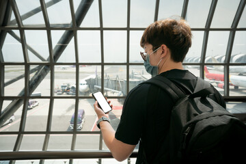 Mobile screen blank on young asian man hand at airport check-in counter background.