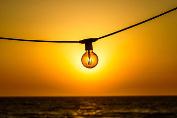 Concept of solar energy. Sun shines trhrough the modern energy saving filament led bulb edison...