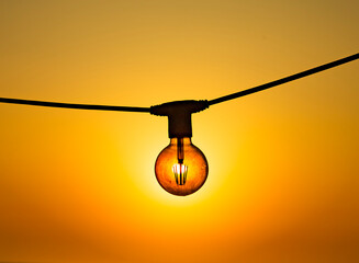 Concept of solar energy. Sun shines trhrough the modern energy saving filament led bulb edison...
