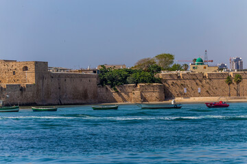 Acre Acco, Israel, June 2022 : view from the sea to the bay, pier, fortress wall and fishing boats...