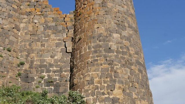 wall and towers of an ancient stone fortress against a blue cloudy sky. Partially destroyed historical building defensive wall of the fortress