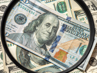 Close-up of hundred dollar bill through a magnifying glass, with old 100  dollar  cash background 