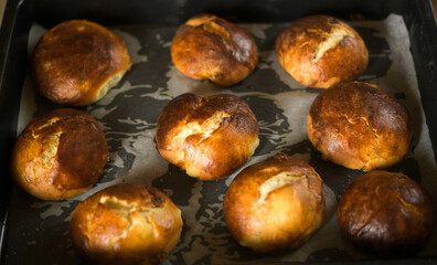  Hot easter buns on cooking paper and baking tray.  Traditional sweet yeast dinner rolls.