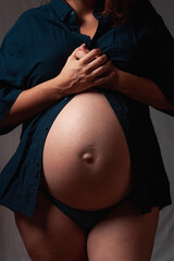 Mujer embarazada sobre fondo gris, concepto maternidad.