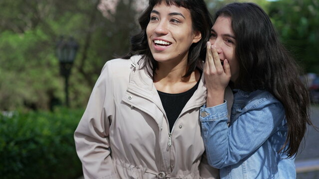 Two Female Friends Gossiping While Walking Outside In Street. Young Women Conversation On Sidewalk