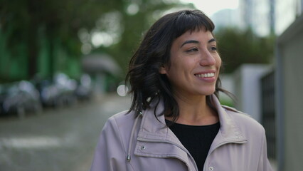 Happy young woman walking outside. One confident hispanic Brazilian girl walks outdoors in street...