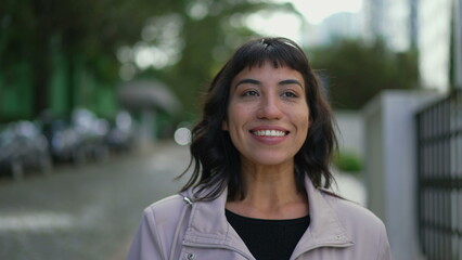 Happy young woman walking outside. One confident hispanic Brazilian girl walks outdoors in street smiling