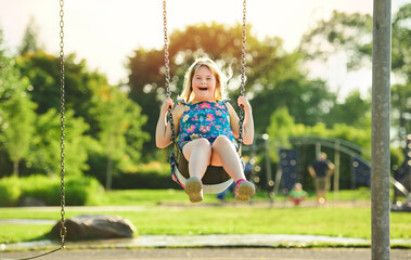 Trisomy 21 child having fun outside at the playground swing