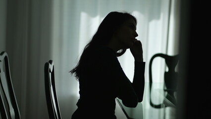 Depressed Young woman sitting alone suffering from mental illness. Silhouette of thoughtful person