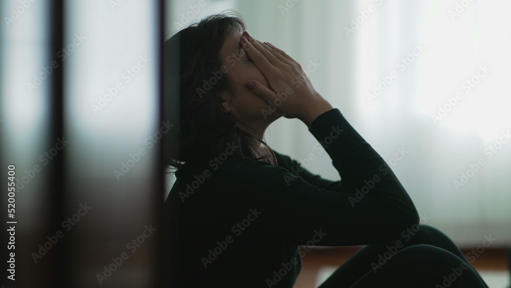 Wall mural Depressed woman sitting on floor covering face with hands in despair