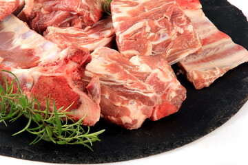 Pieces of raw meat on a round black stone plate on a white background, Fresh meat with bones