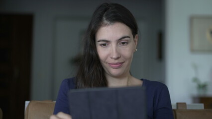 Close up woman face looking at tablet screen smiling. Portrait person reading content online with modern digital device