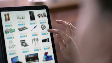 Fototapeta na wymiar Closeup hand holding tablet browsing online shopping. Person looking for household product on website store selecting item