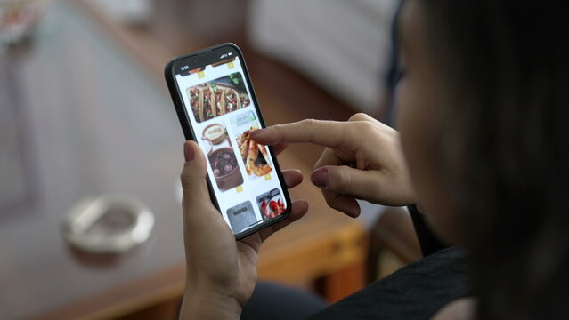 Closeup hands browsing online food app menu searching what to eat. Female hand searching for food