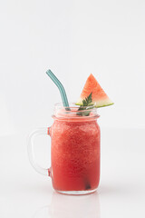 red watermelon smoothie in a tall glass decorated with piece of watermelon isolated